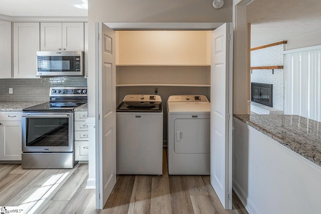 interior space with appliances with stainless steel finishes, white cabinets, independent washer and dryer, and light stone countertops