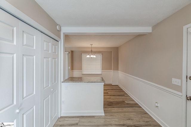 interior space with a textured ceiling, a chandelier, and light wood-style floors