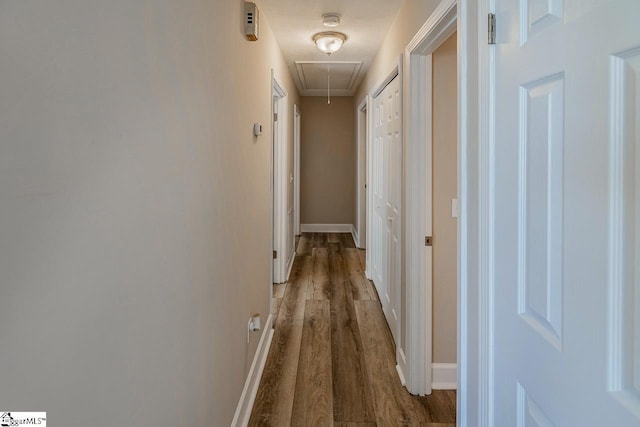 hallway with attic access, baseboards, and wood finished floors
