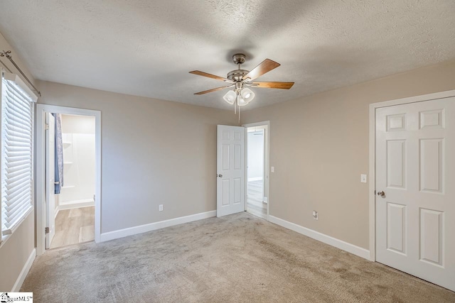 unfurnished bedroom featuring light carpet, a textured ceiling, and baseboards