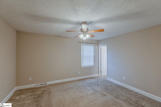 spare room featuring visible vents, light carpet, ceiling fan, a textured ceiling, and baseboards