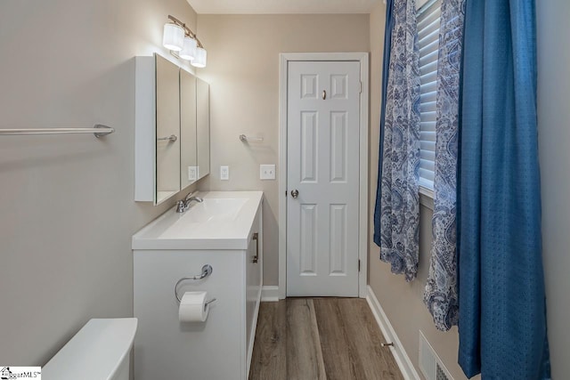 bathroom featuring baseboards, visible vents, wood finished floors, and vanity