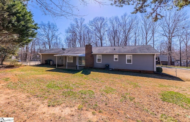 back of house featuring a yard, a chimney, and fence