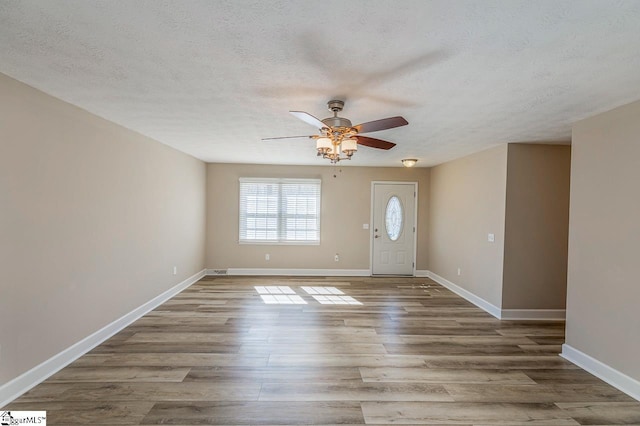 entrance foyer with light wood finished floors, baseboards, and a textured ceiling