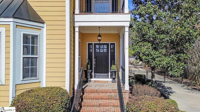 entrance to property with fence and a balcony