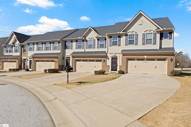 multi unit property featuring a garage, concrete driveway, and brick siding