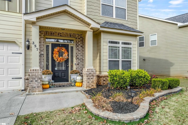 property entrance with a garage, a shingled roof, and brick siding