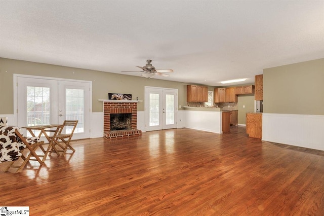 unfurnished living room with a wainscoted wall, french doors, and dark wood-type flooring