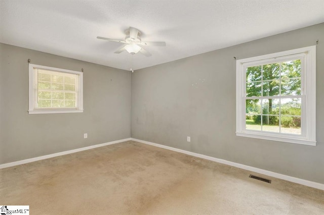 carpeted spare room with visible vents, ceiling fan, and baseboards