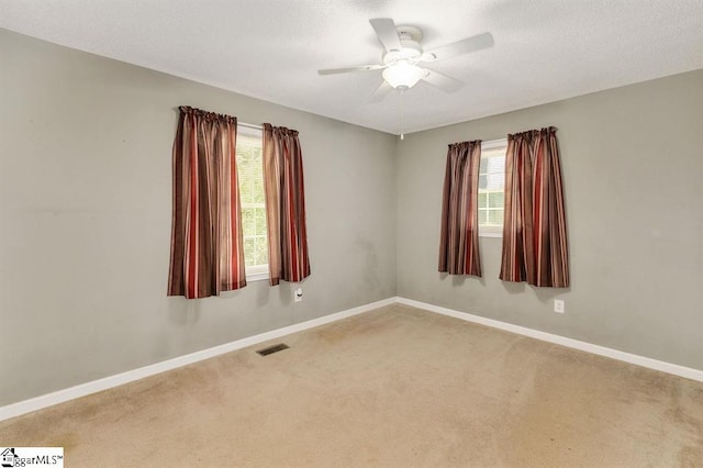 empty room featuring carpet floors, visible vents, and baseboards