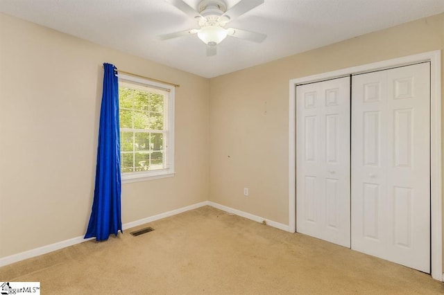 unfurnished bedroom with a closet, visible vents, light carpet, and baseboards