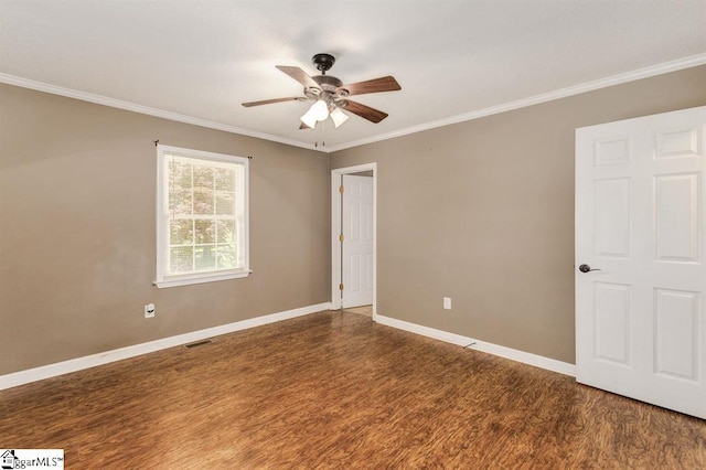 spare room with ceiling fan, visible vents, baseboards, dark wood-style floors, and crown molding