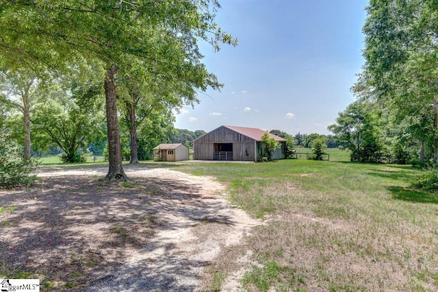 view of yard with an outbuilding, a detached garage, fence, an outdoor structure, and driveway