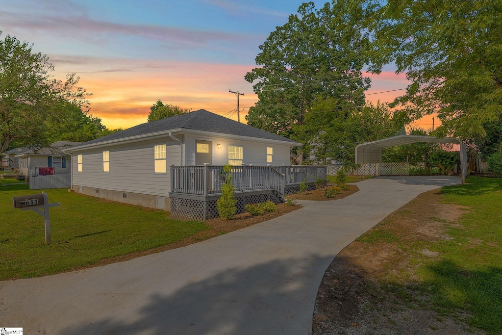 view of front of property featuring a deck, a yard, driveway, crawl space, and a detached carport