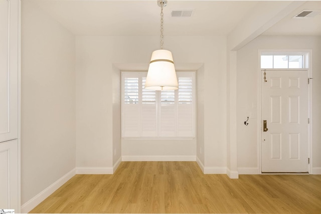 unfurnished dining area with light wood-type flooring, baseboards, and visible vents