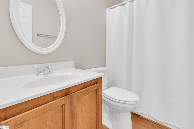 bathroom with toilet, wood finished floors, and vanity