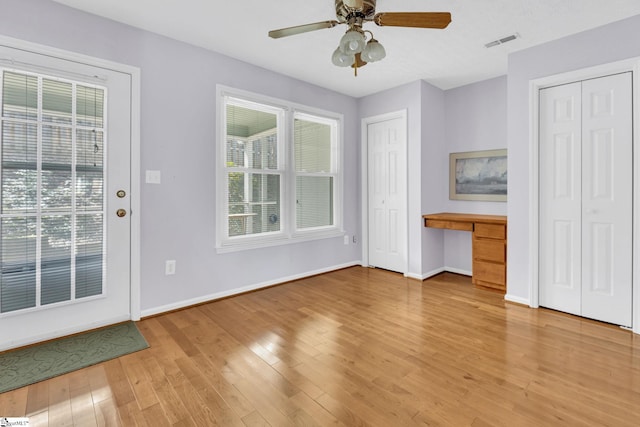 interior space with light wood-type flooring, baseboards, visible vents, and built in desk