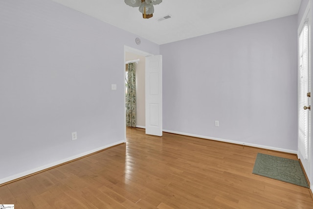 empty room with light wood-style flooring, visible vents, ceiling fan, and baseboards