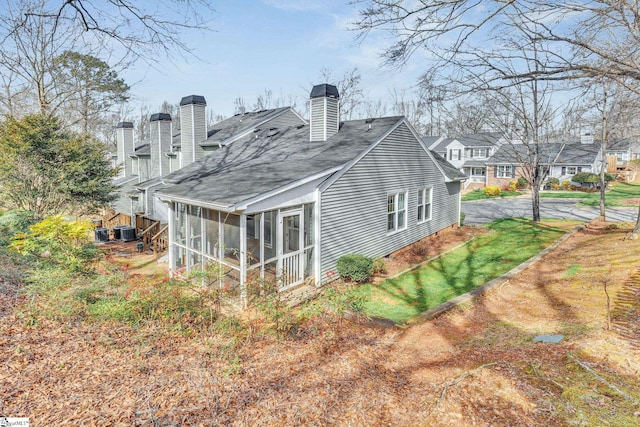 rear view of house featuring a sunroom, central AC, and a chimney