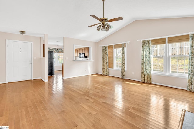 unfurnished living room with light wood-type flooring, a ceiling fan, a wealth of natural light, and lofted ceiling