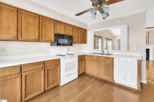 kitchen with light wood-type flooring, white appliances, light countertops, and a sink