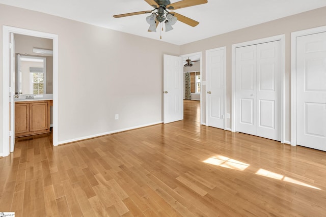 unfurnished bedroom with a ceiling fan, light wood-style flooring, baseboards, and two closets