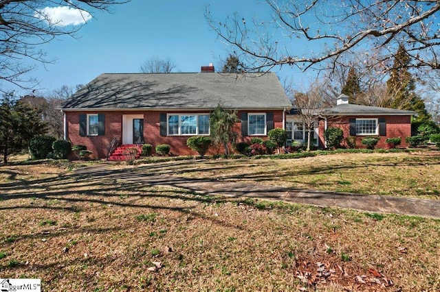 view of front facade featuring a front yard, brick siding, and a chimney