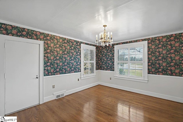 unfurnished room featuring wallpapered walls, visible vents, and a wainscoted wall