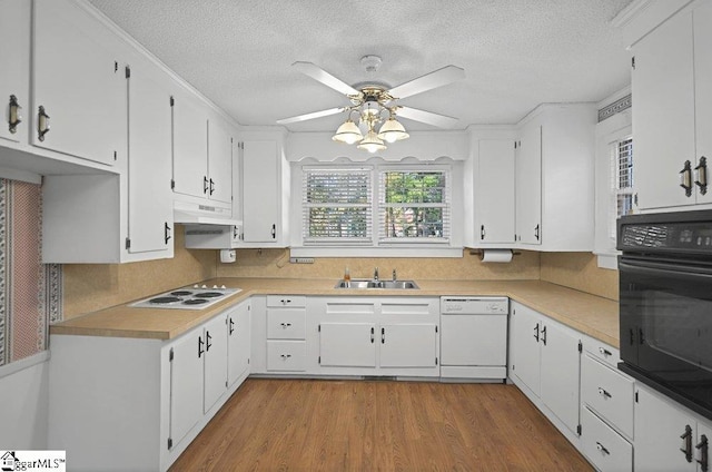 kitchen with light countertops, white appliances, a sink, and white cabinets