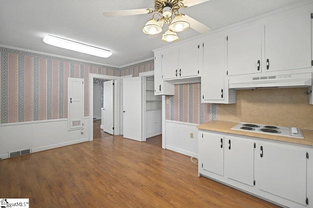 kitchen with light countertops, white cabinetry, wallpapered walls, and under cabinet range hood