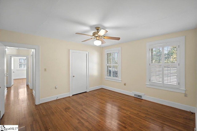 unfurnished bedroom featuring dark wood-type flooring, a ceiling fan, visible vents, and baseboards