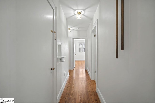 corridor featuring baseboards and wood finished floors