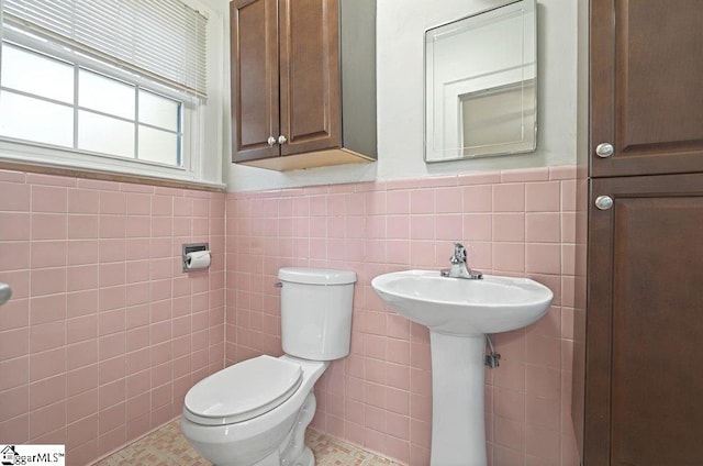 bathroom with toilet, tile walls, and wainscoting