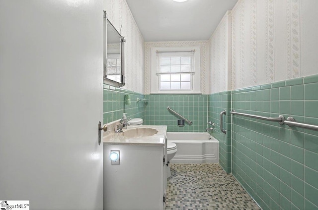 full bathroom featuring wallpapered walls, wainscoting, tile walls, and vanity