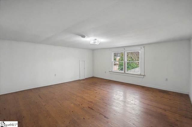 spare room featuring baseboards and wood finished floors