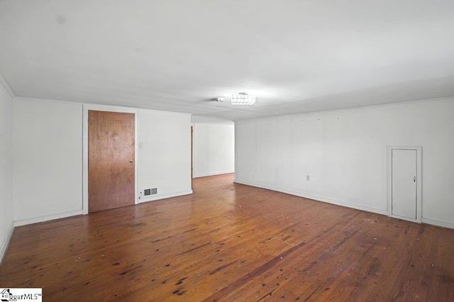 empty room featuring baseboards, visible vents, and wood finished floors