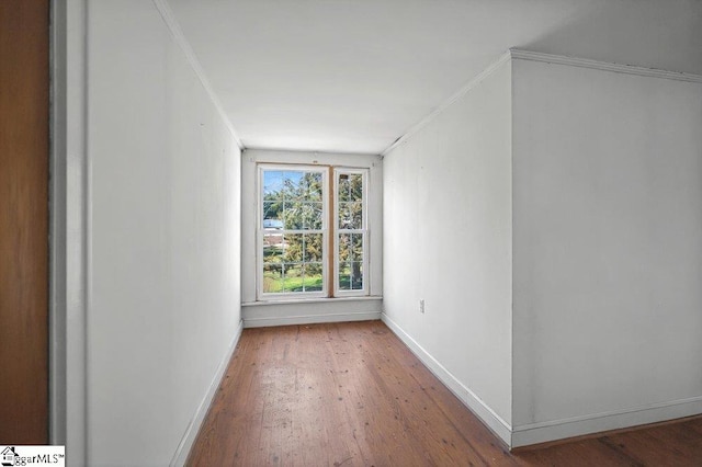 unfurnished room featuring baseboards, wood finished floors, and crown molding