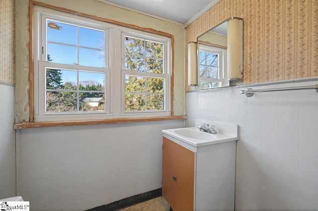 bathroom with tile walls, a wainscoted wall, vanity, and wallpapered walls