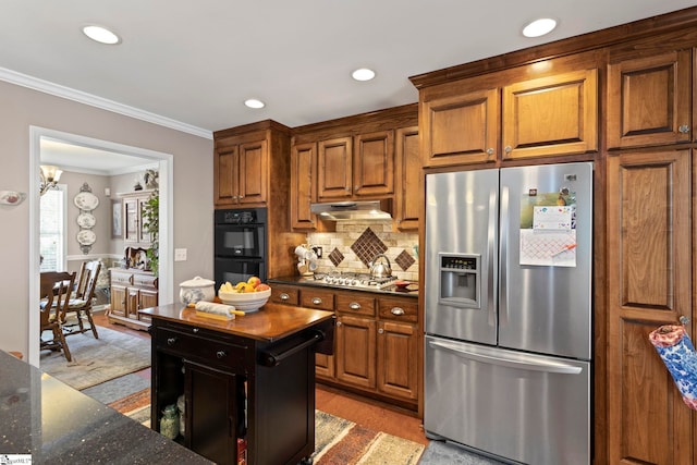 kitchen with stainless steel appliances, decorative backsplash, ornamental molding, dark stone countertops, and under cabinet range hood