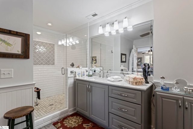 bathroom with a wainscoted wall, visible vents, ornamental molding, a stall shower, and vanity