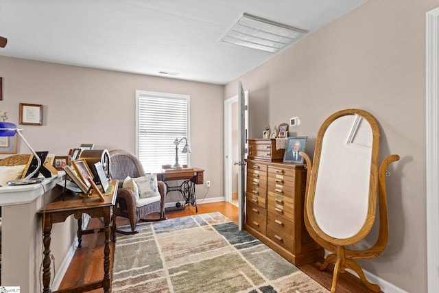 living area featuring wood finished floors, visible vents, and baseboards