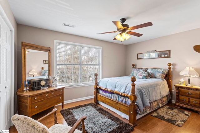 bedroom with visible vents, ceiling fan, baseboards, and wood finished floors