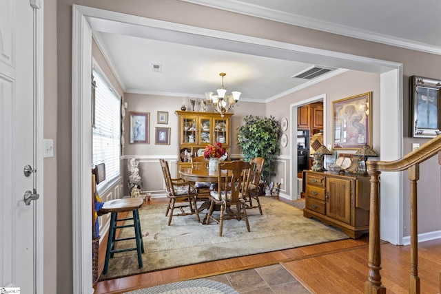 dining room featuring ornamental molding, wood finished floors, visible vents, and a notable chandelier