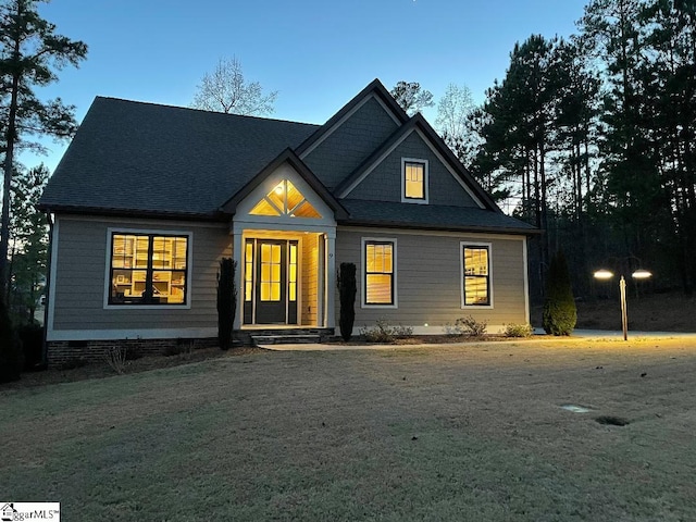 view of front facade with a shingled roof, crawl space, and a front yard