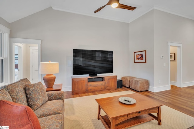 living room with a ceiling fan, light wood-type flooring, vaulted ceiling, and baseboards