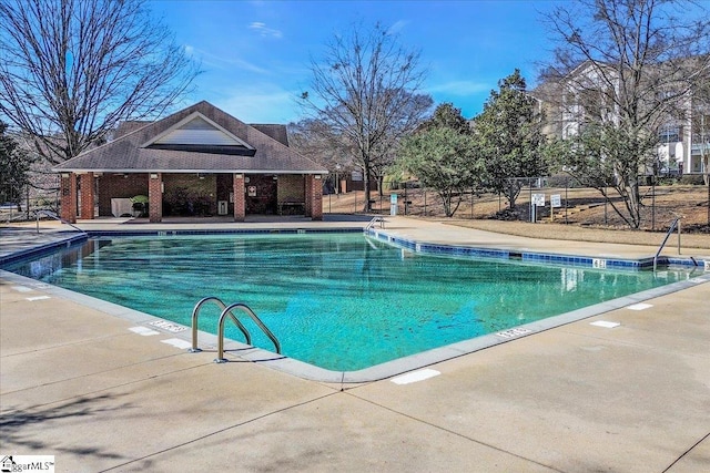 community pool with a patio and fence