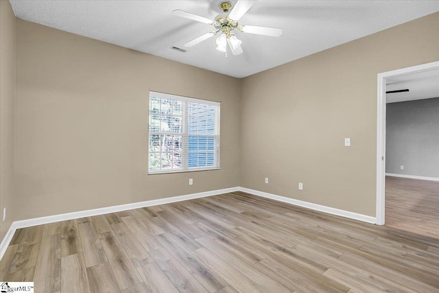 unfurnished room with ceiling fan, a textured ceiling, visible vents, baseboards, and light wood finished floors