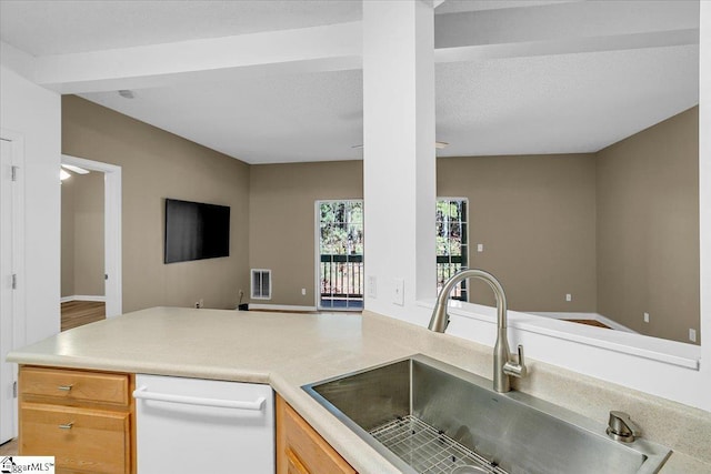 kitchen featuring white dishwasher, a sink, open floor plan, light countertops, and light brown cabinetry