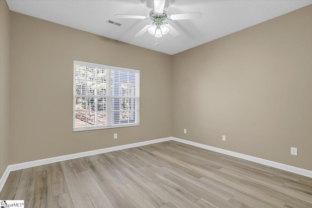 spare room with light wood-type flooring, baseboards, visible vents, and a ceiling fan