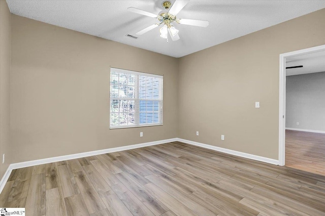 unfurnished room with light wood-type flooring, baseboards, visible vents, and ceiling fan